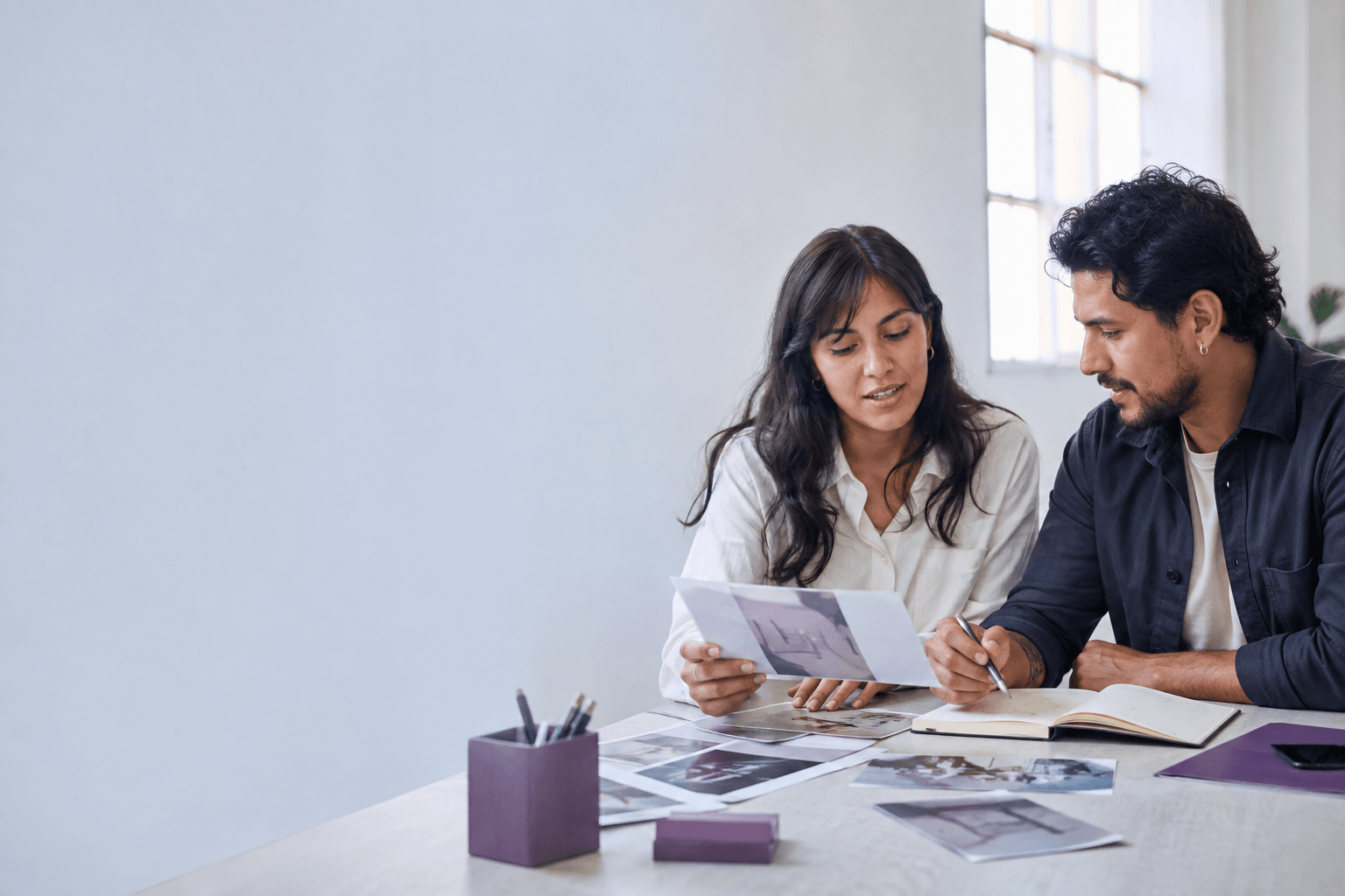 Dos profesionales conversan sobre propuestas creativas en una mesa de trabajo.